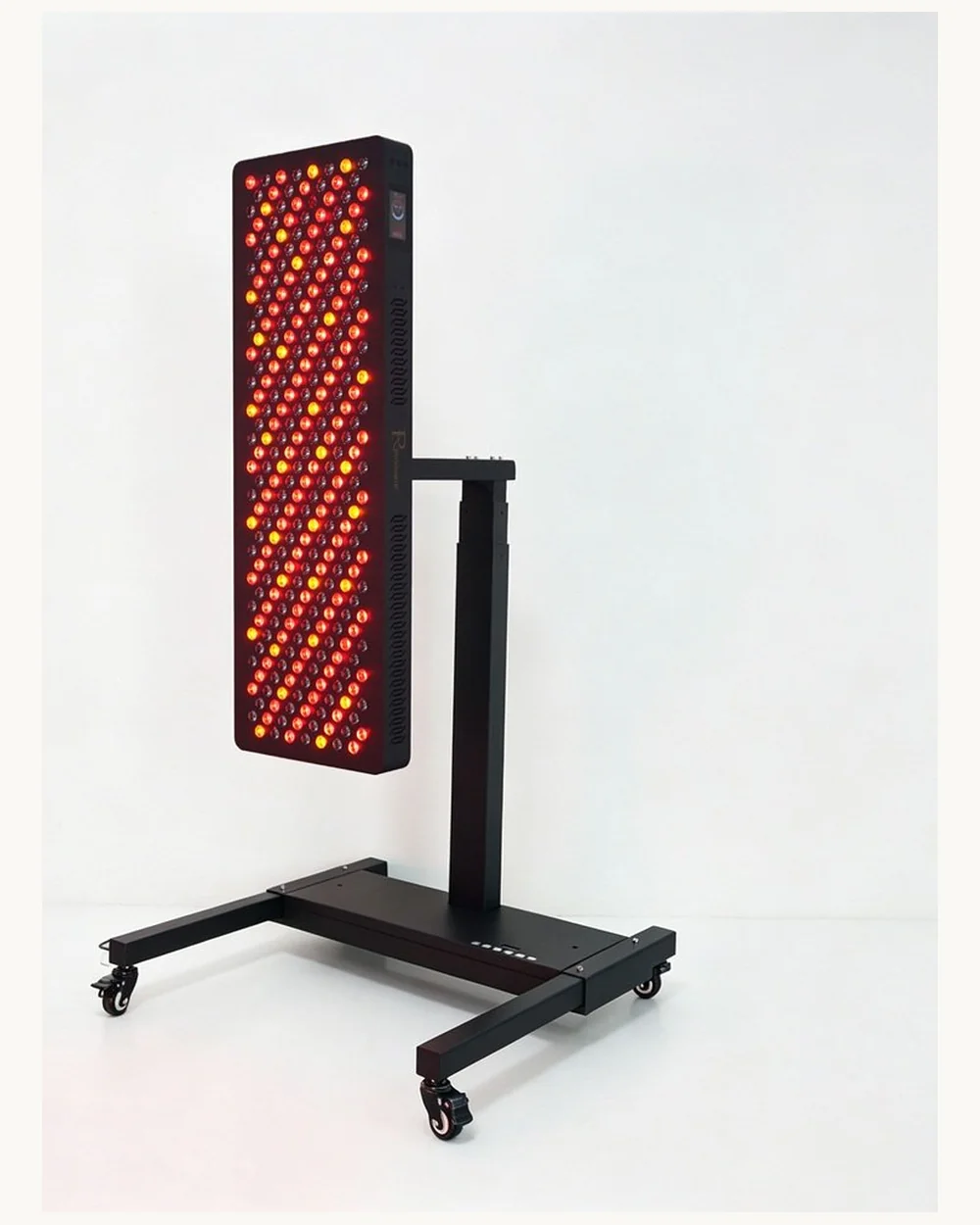 The Rinnovare R-100 targeted red light panel on a stand in a dark studio.